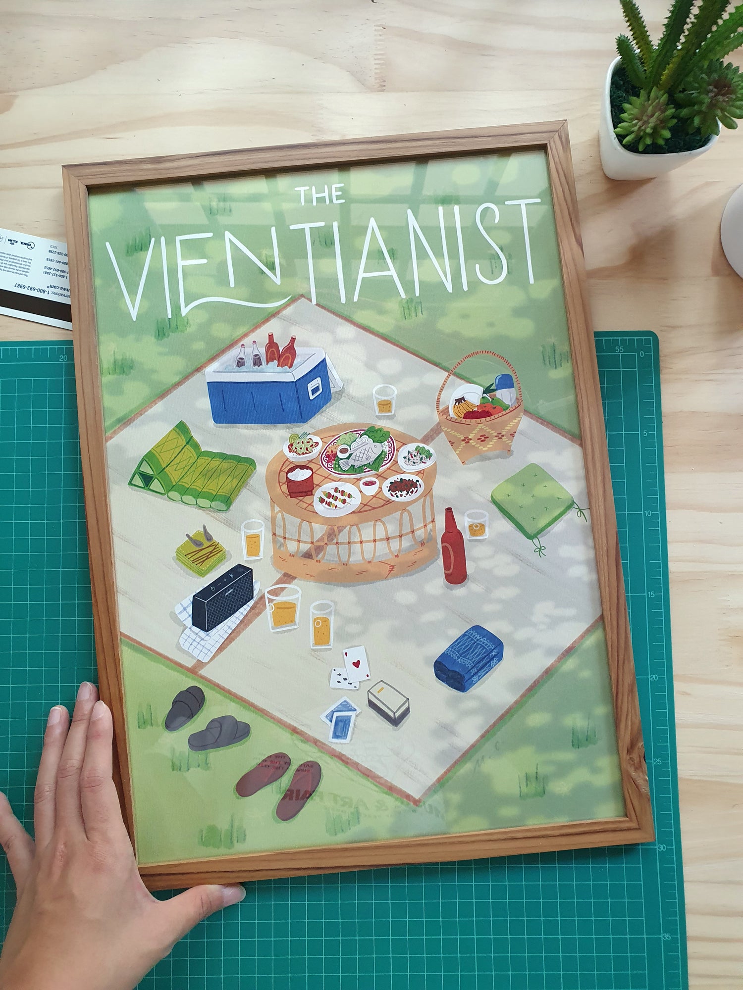 Illustration poster of a Lao picnic by The Vientianist in a frame on a table